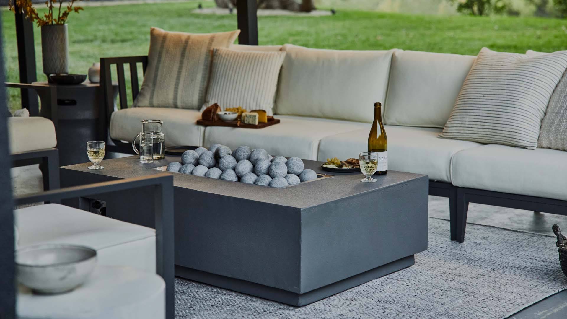 Outer's luxury fire pit featured with the aluminum outdoor sofa and durable, soft outdoor rug.
