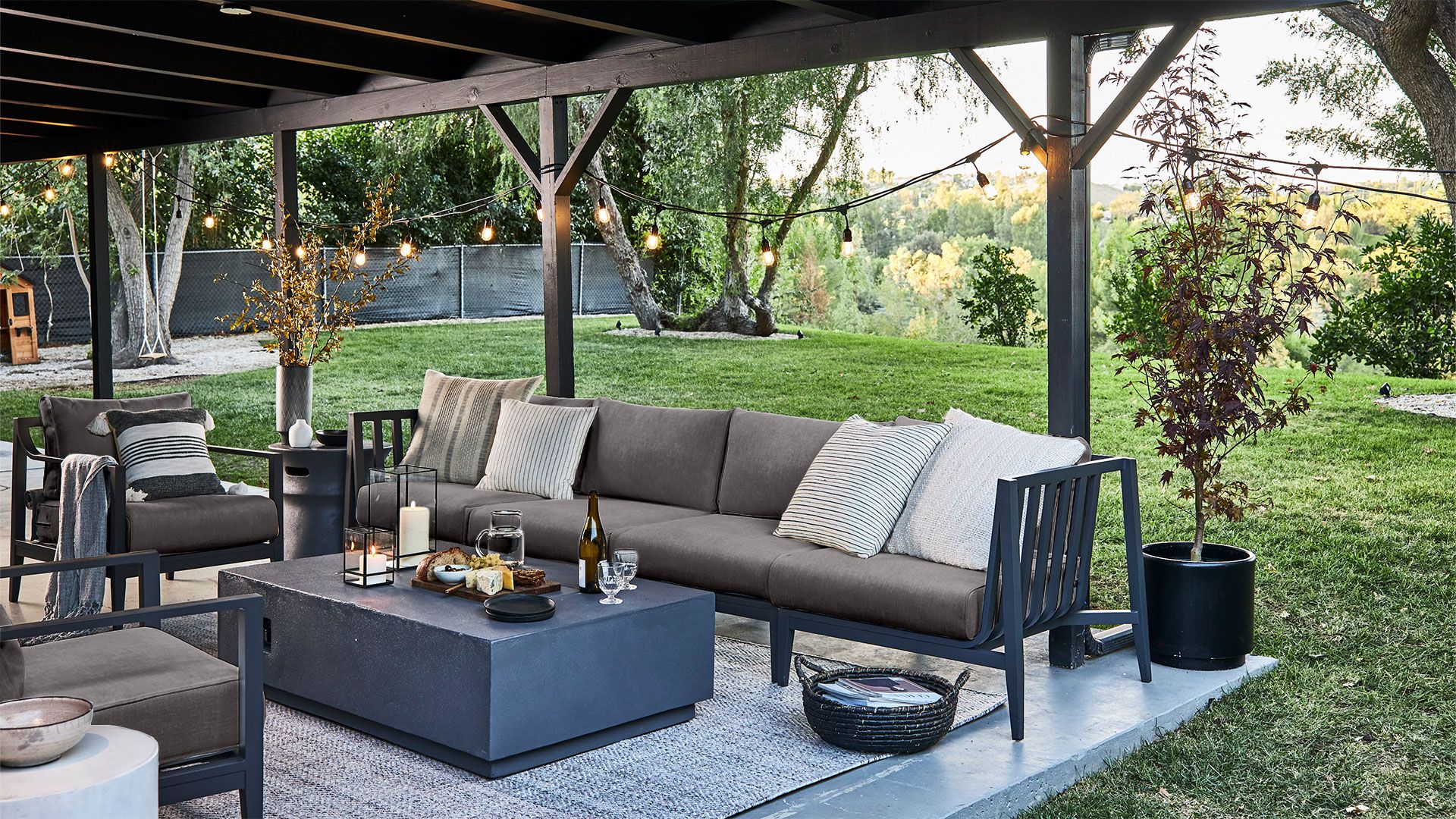 The 4 seat charcoal aluminum sofa and armchairs in pebble gray fabric shown with our sustainably made beige rug.