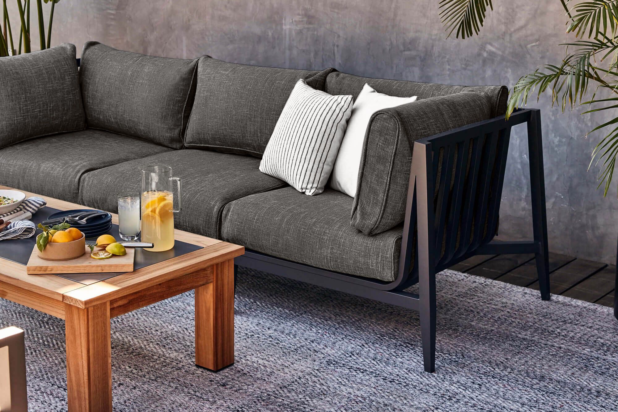 The 3 seat charcoal aluminum sofa in pebble gray fabric shown on top of our durable pebble gray rug.