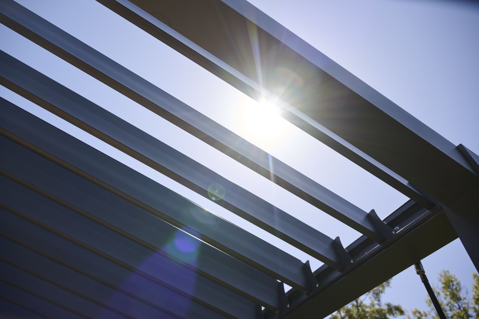 Adjustable louvers filtering sunlight through an Outer Spaces pergola
