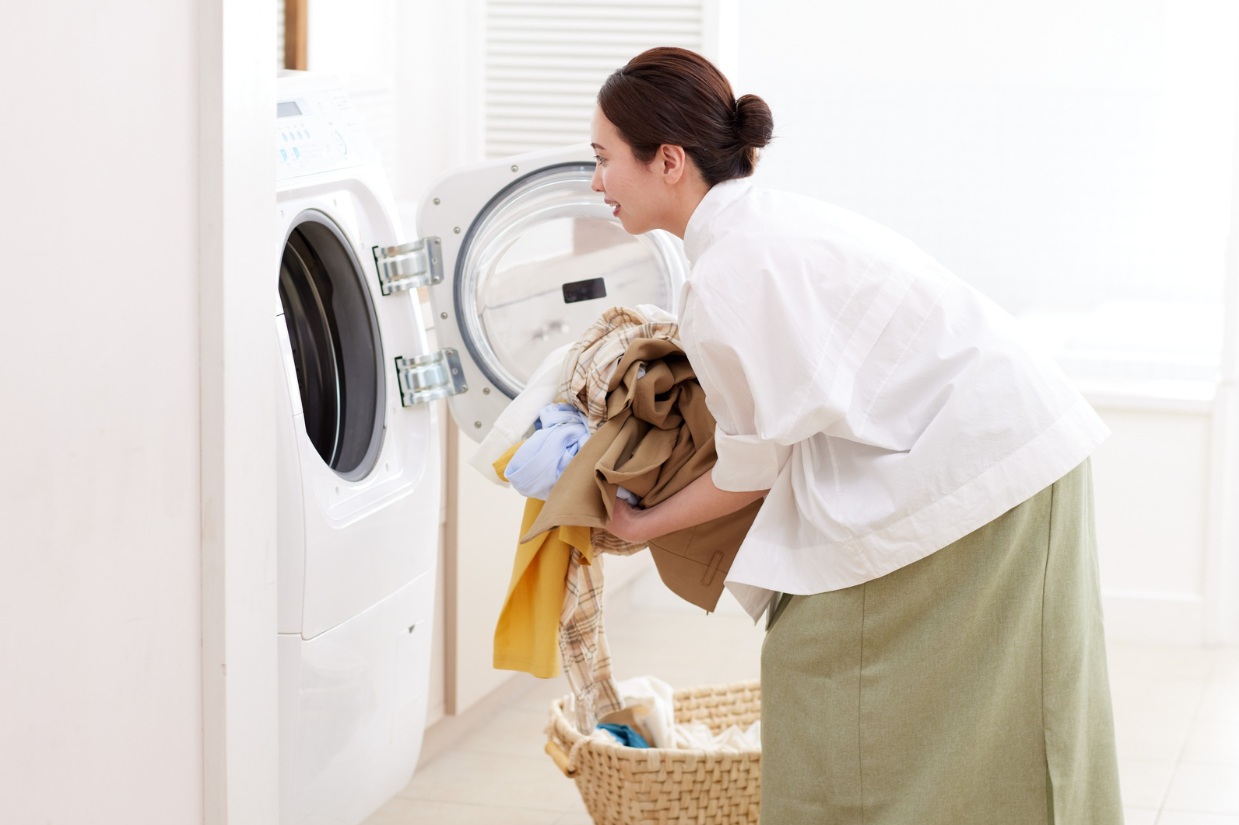 洗濯機に衣類を入れる女性