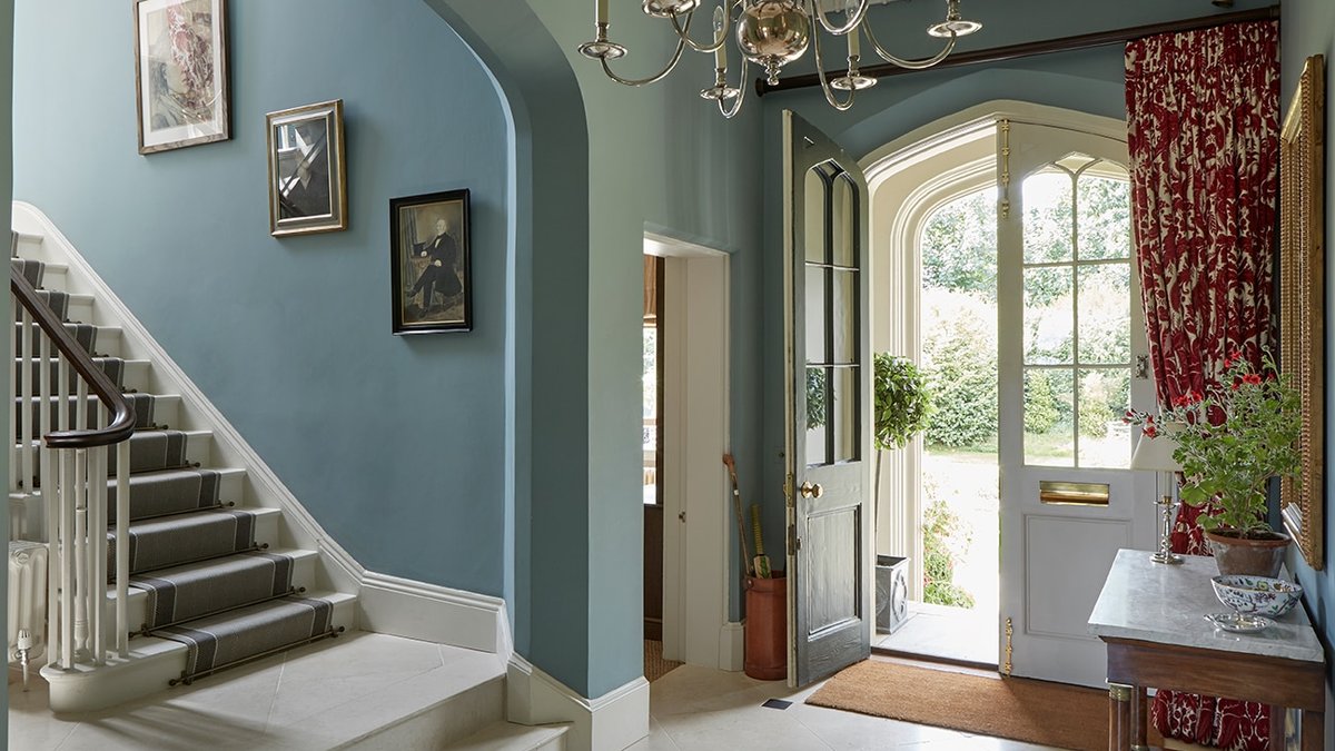 The entrance hall and staircase walls are painted in Oval Room Blue by Farrow & Ball.