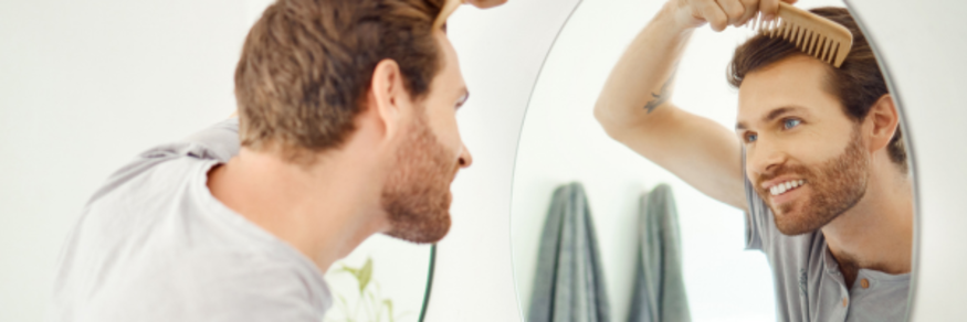 man looking in the mirror and smiling while combing his hair