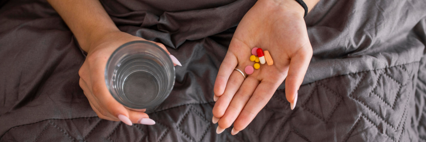 woman holding colourful medication and a glass of water