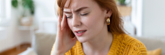 Woman in pain and holding head from migraine headache