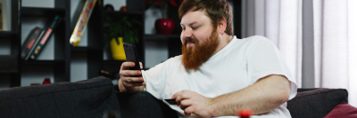 Ginger man sat on his sofa looking at his phone
