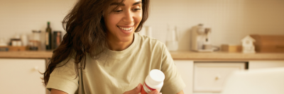 Girl smiling at bottle of weight loss tablets