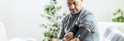 Man in grey t-shirt checking his blood pressure at home