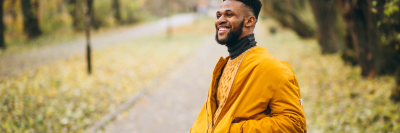 Man smiling in nature wearing a yellow jacket and black turtle neck