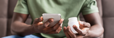 Man taking pills and looking at phone