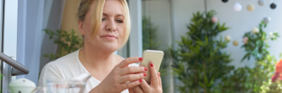 Blond woman looking at phone in cafe