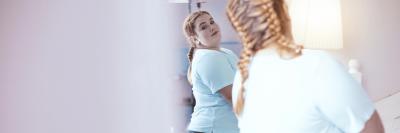 woman looking at her body in the mirror