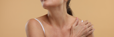 older woman touching her shoulder in white vest top