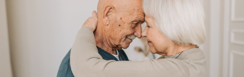 an older couple cuddling and smiling at each other