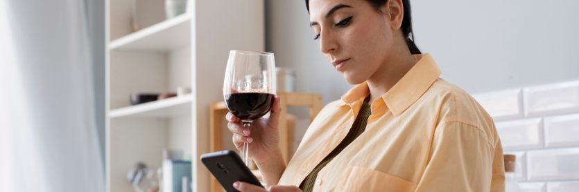lady drinking red wine and looking at her phone