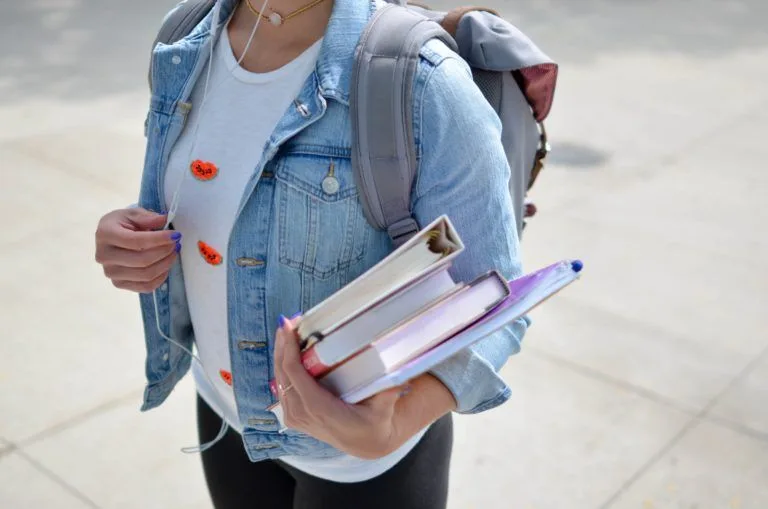 student-wearing-backpack-holding-books