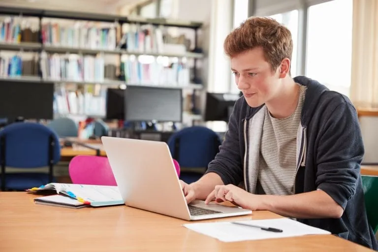 male-student-in-library-using-laptop