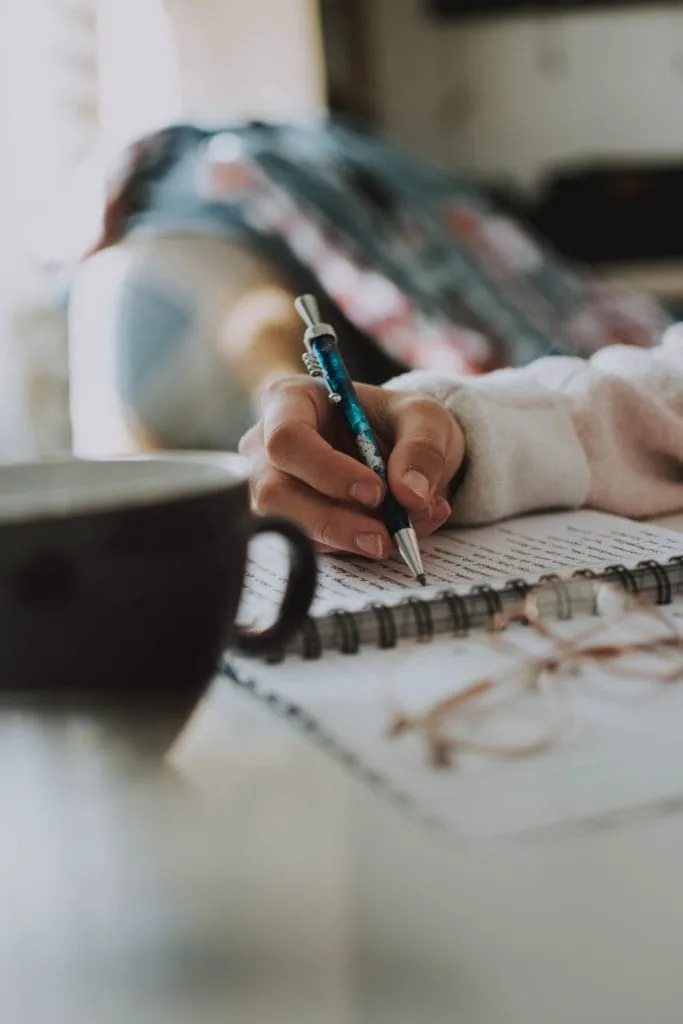 person-writing-in-notebook-on-desk