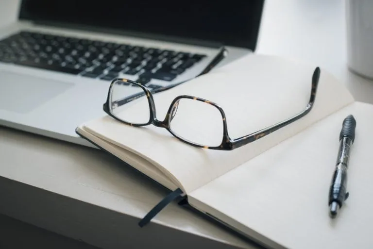 glasses-on-open-notebook-next-to-computer