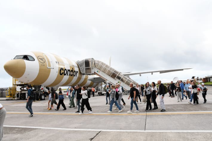 Photo of Condor plane with passengers disembarking around it.