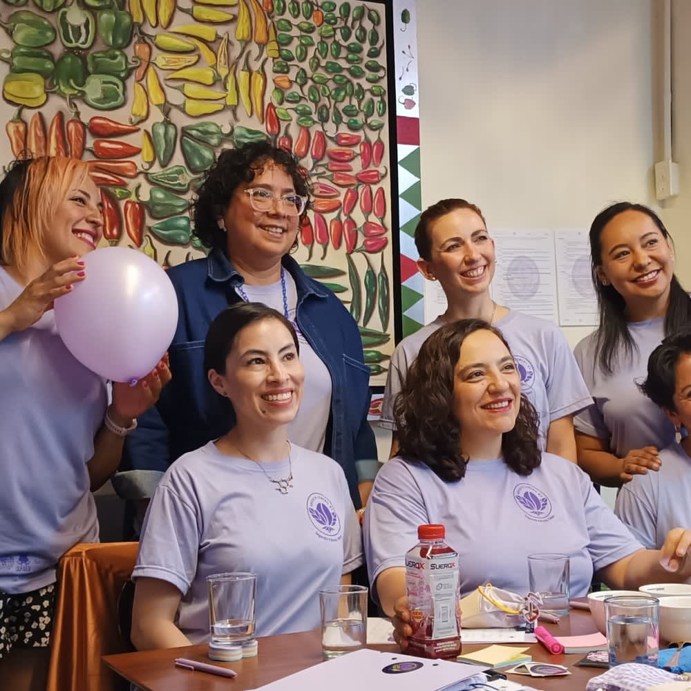 Collaborators in the certamen's lilac t-shirts smile around a table