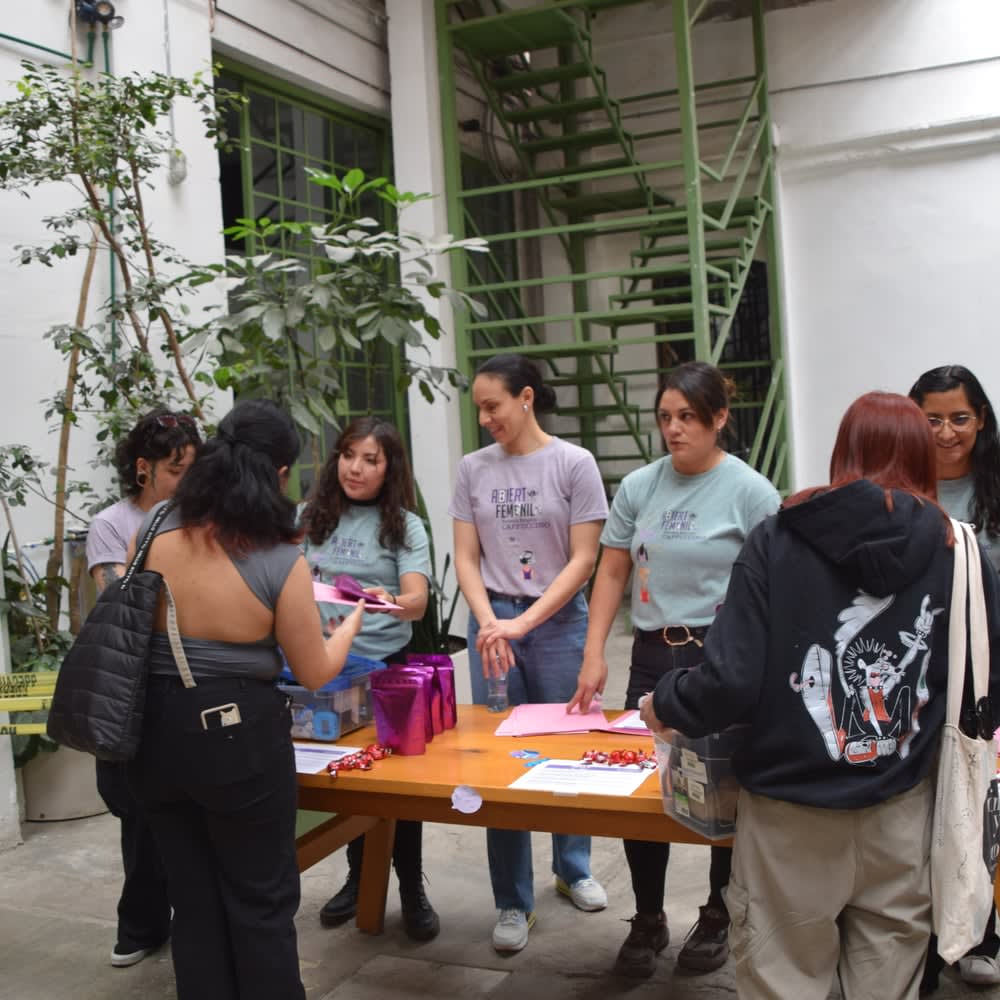 Collaborators hand out purple bags at a table in the courtyard
