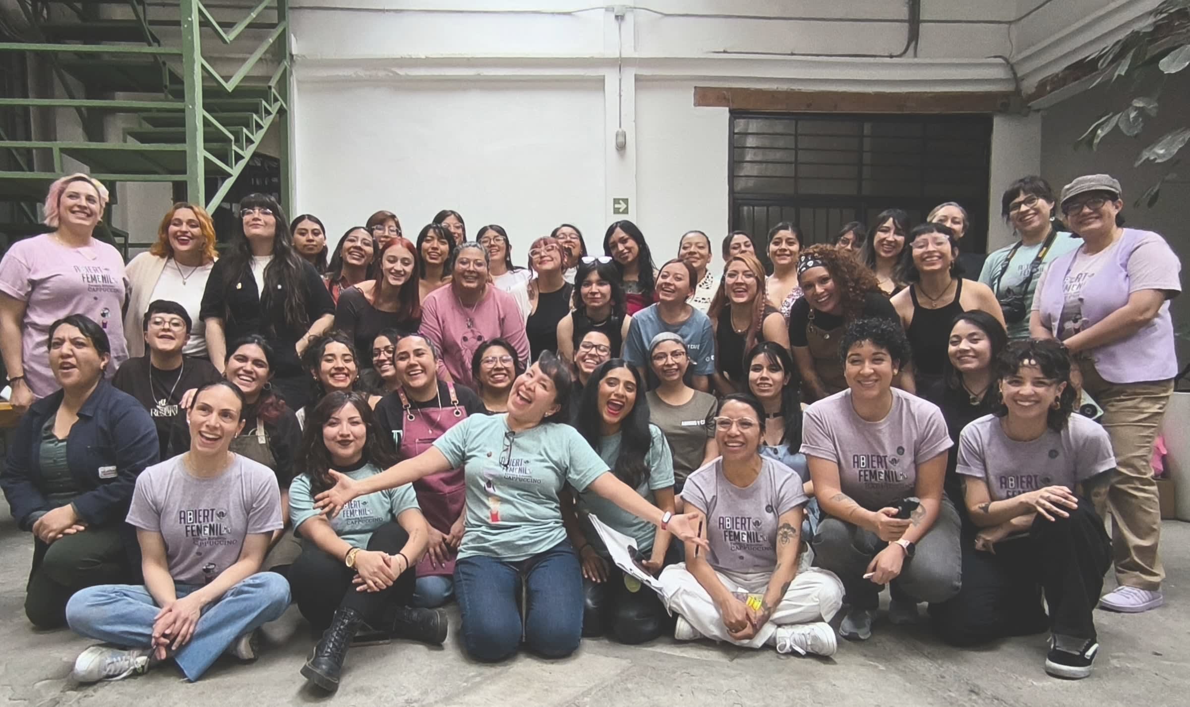 Dozens of women from the certamen gathered in a courtyard, those in front sitting on the floor