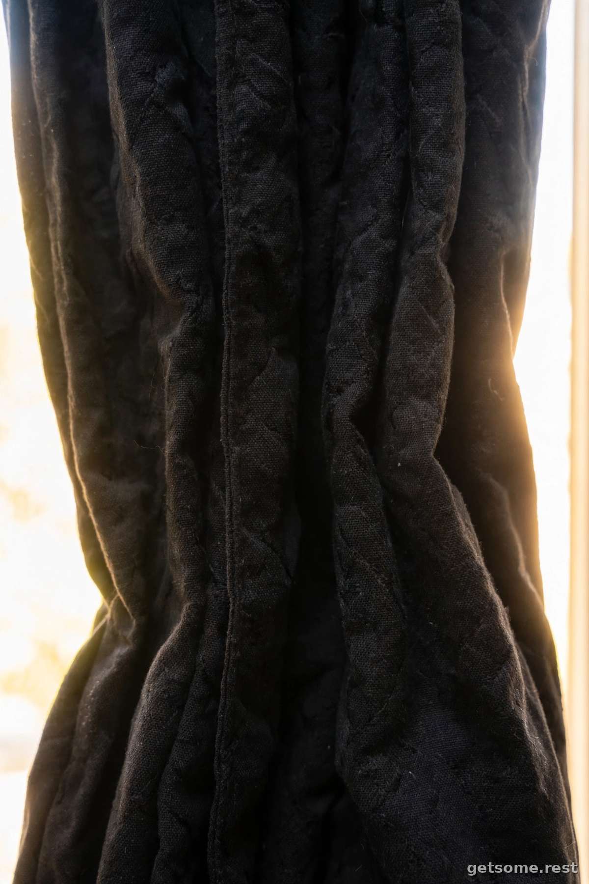Blackout curtains fully closed over a bedroom window on a bright day