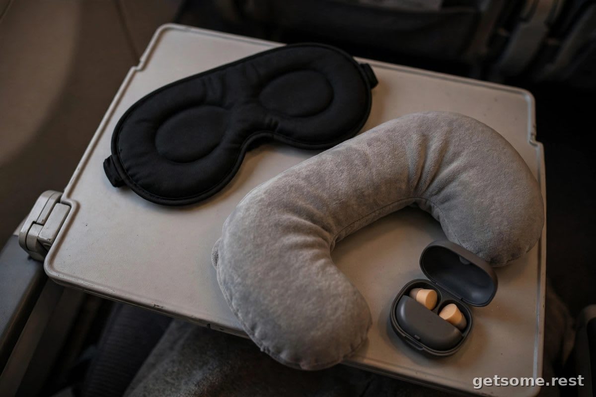 Travel sleep kit with eye mask, neck pillow and earplugs on a tray table