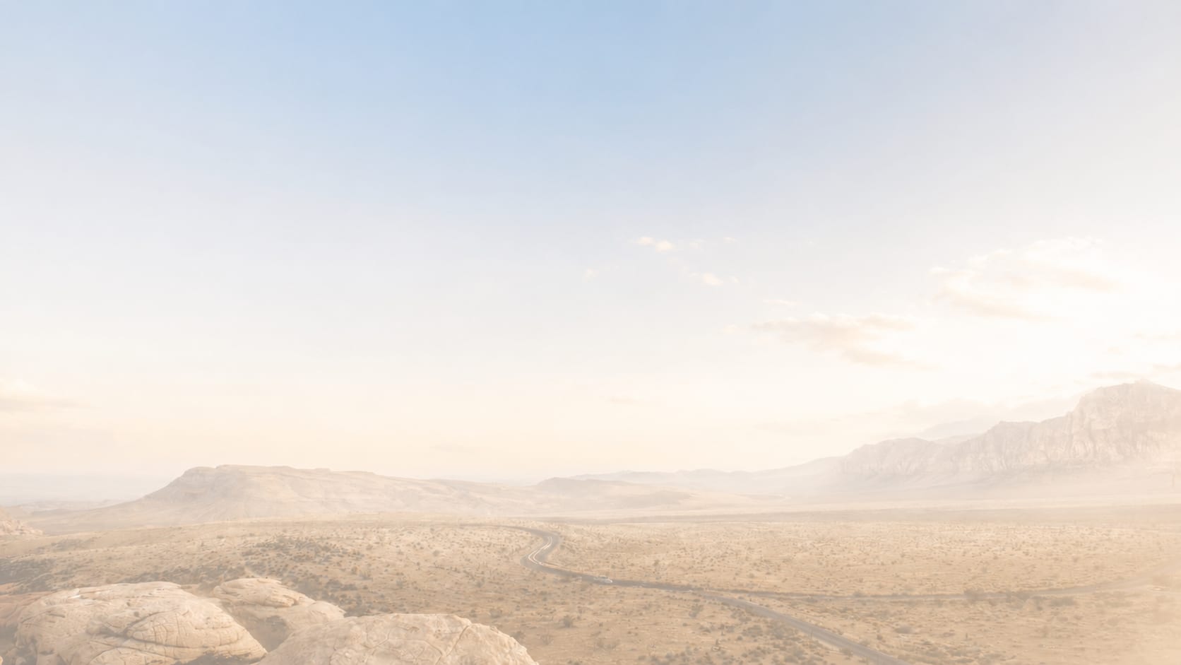 Mountain range rising above a sea of clouds in warm, muted light