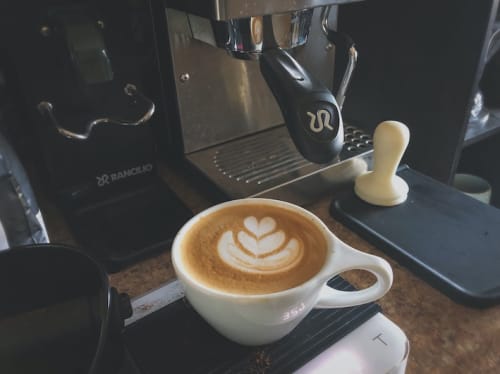 A picture of a flat white next to a coffee machine