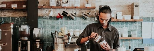 A barista in a cafe about to pour coffee