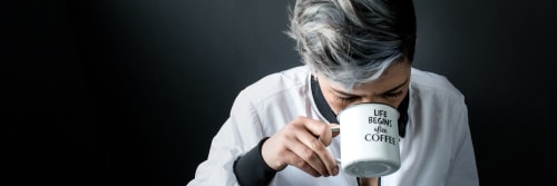 Woman drinking from a mug reading 'Life Begins after Coffee'