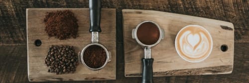 Four different coffee grinds and a cup of coffee on a bread board