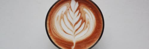 Top down view of a cup of coffee with an intricate milk pattern