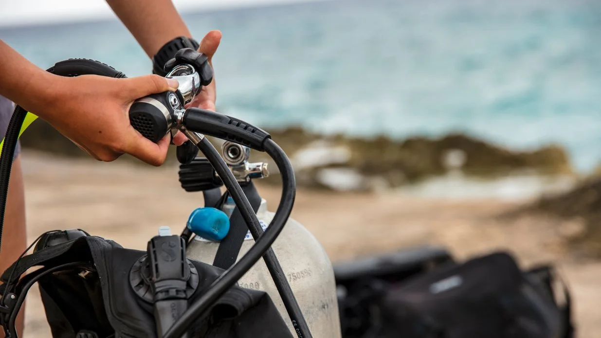 Diver mounting regulator on a tank