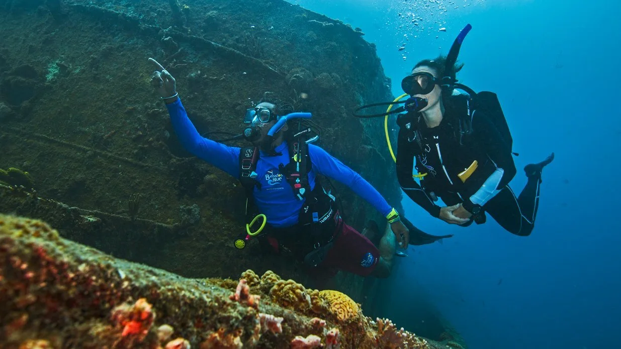 divers next to a ship wreck