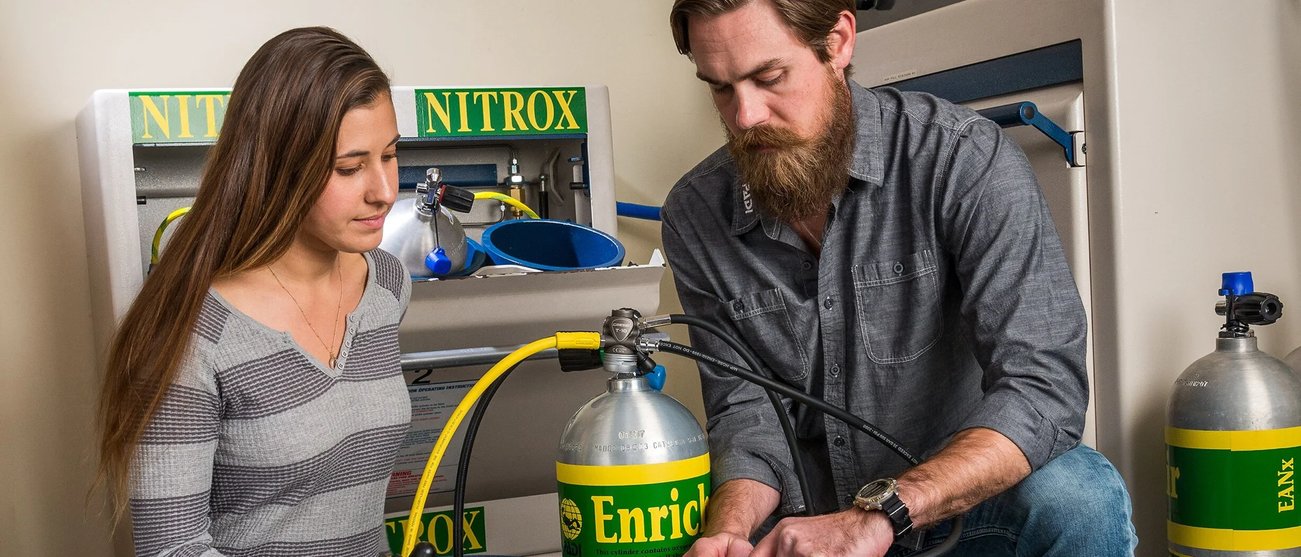 two people analyzing nitrox tanks