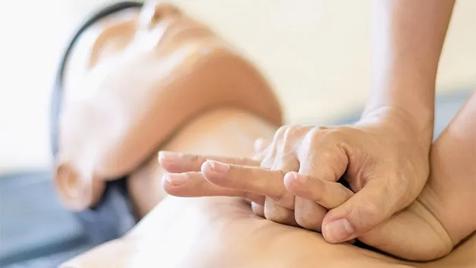 A person shows where to position your hands when doing CPR.