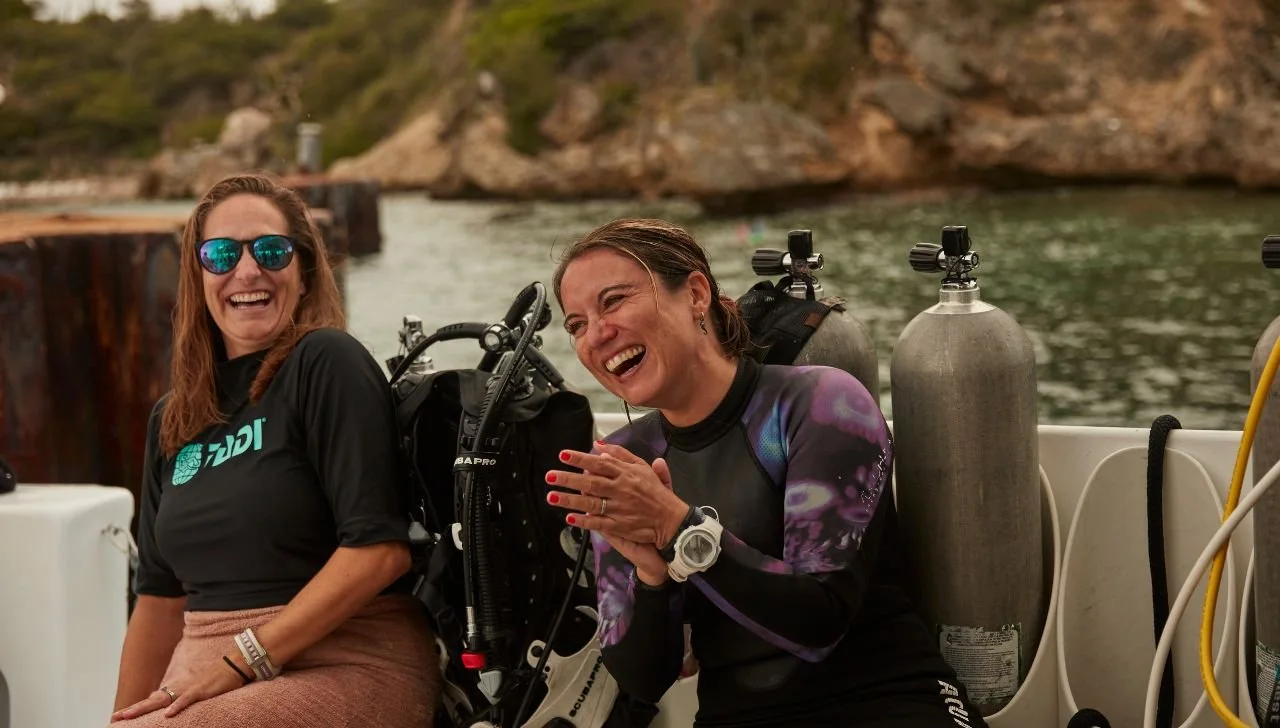 Two female divers sitting on a dive boat