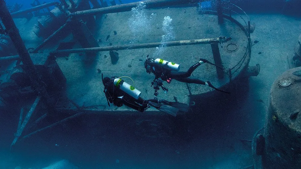 Diver diving along a ship wreck