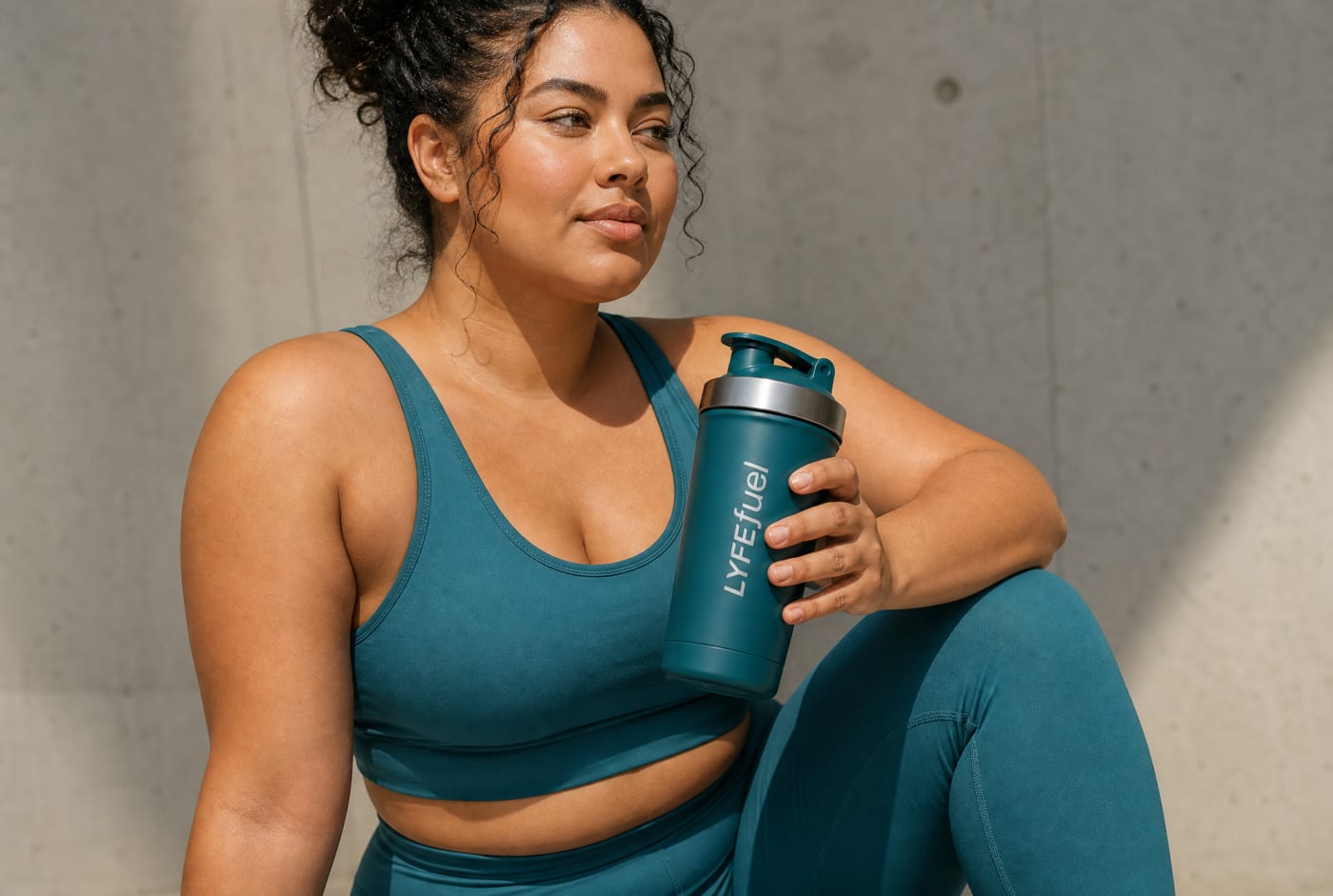 Woman in athletic wear holding LyfeFuel shaker
