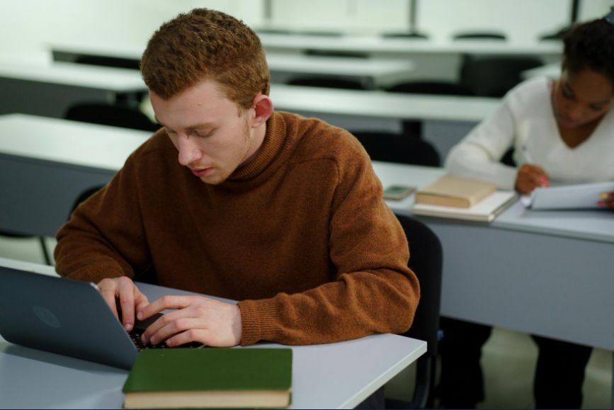 man-typing-in-brown-sweater-laptop.jpg