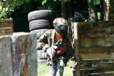 Chłopiec grający w paintball skradający się za drewnianym płotkiem