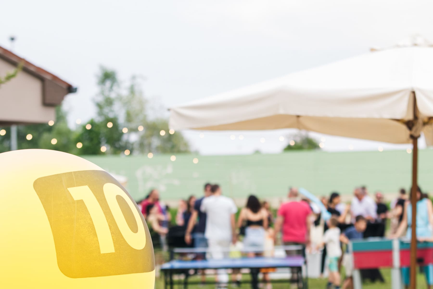 Una fotografia che mostra la festa con in primo piano uno dei palloncini gialli usati come decorazione e sullo sfondo i partecipanti, visti però sfocati