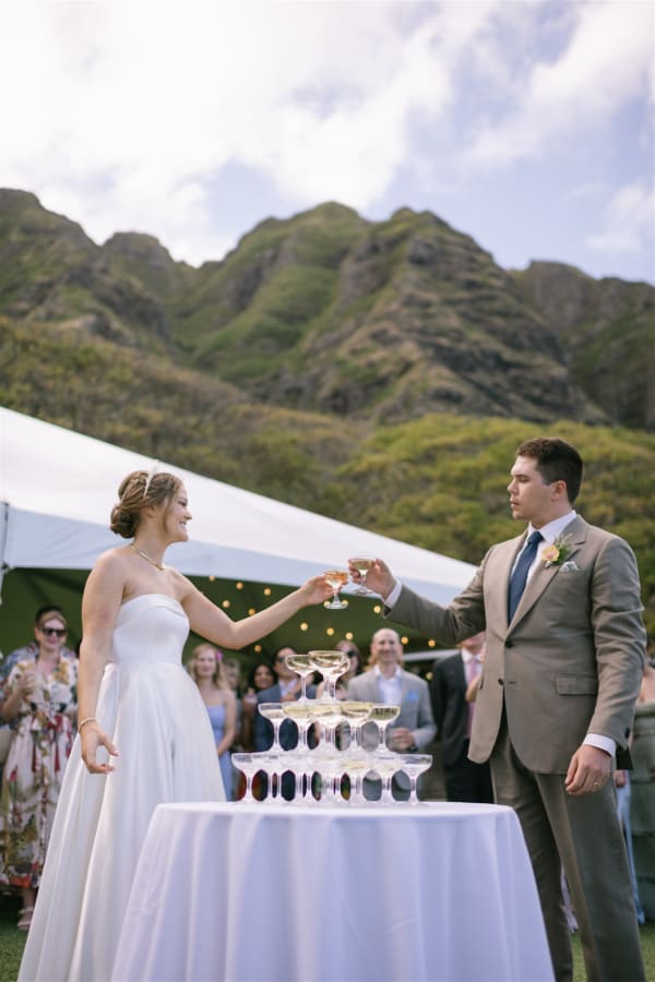 Bride and groom toasting a champagne tower at Pālikū Gardens at Kualoa Ranch on Oahu