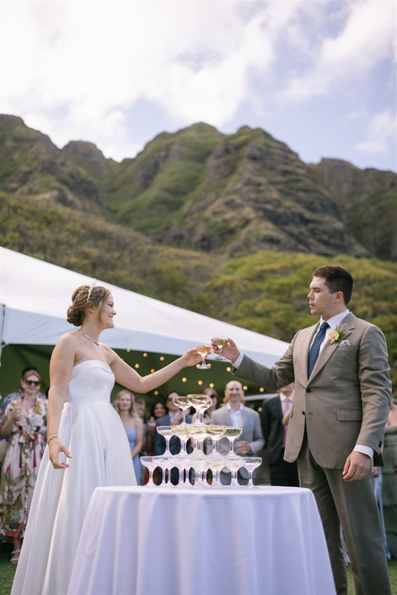 Bride and groom toasting a champagne tower at Pālikū Gardens at Kualoa Ranch on Oahu