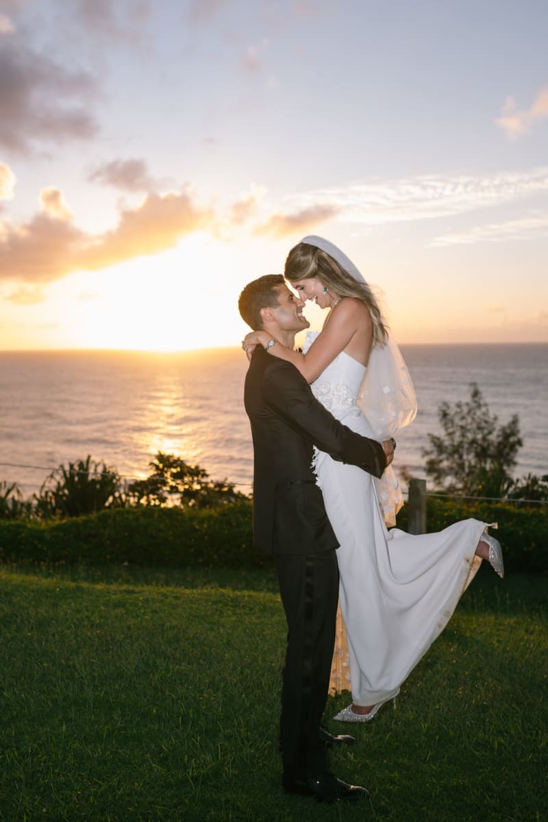Groom lifting his bride at sunset above Hanalei Bay on Kauai