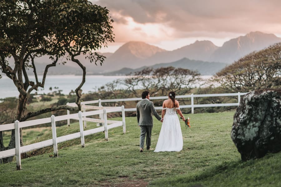 Couple walking the fence line at Pālikū Gardens with the Ko'olau ridge behind