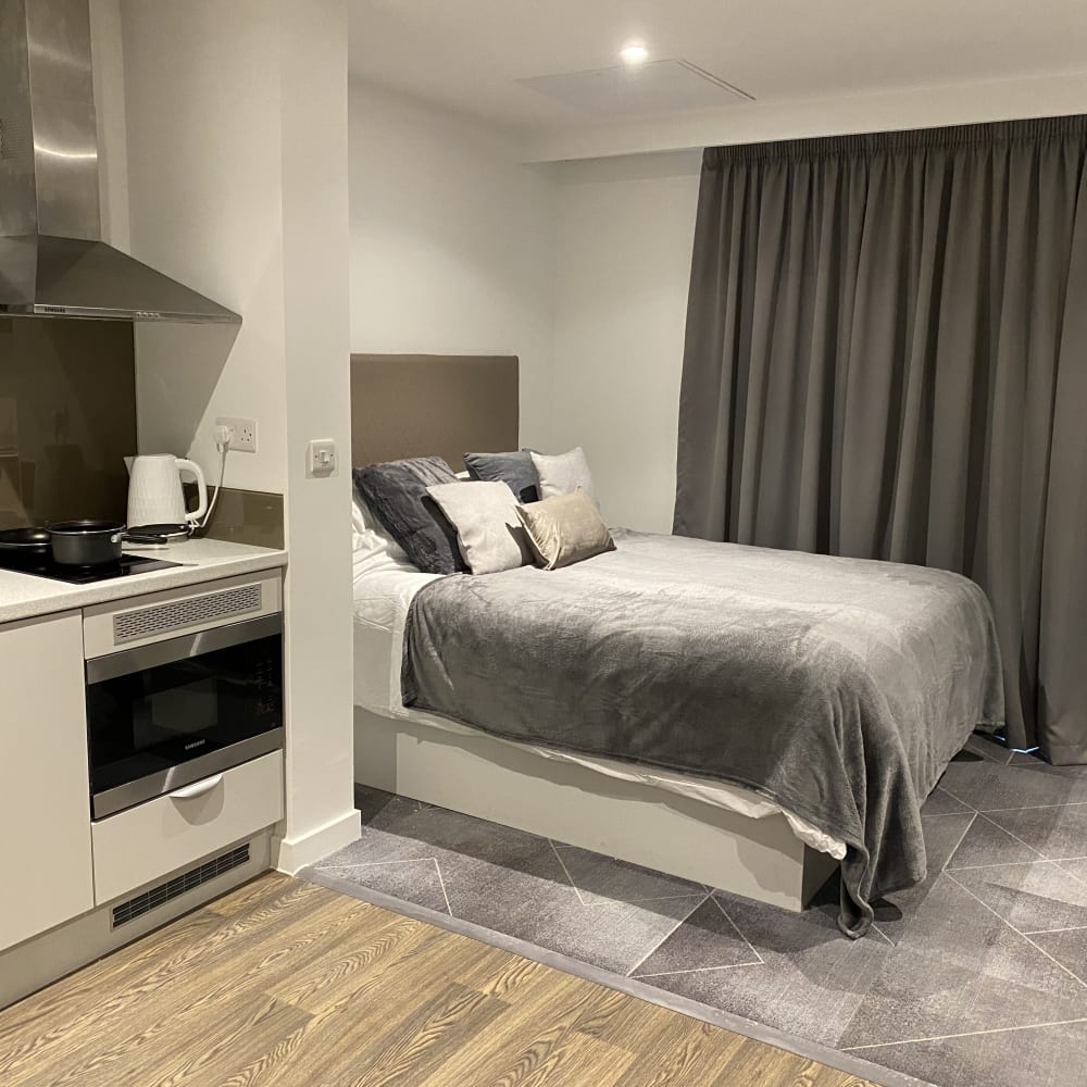 Glasgow student room with grey bed and kitchen